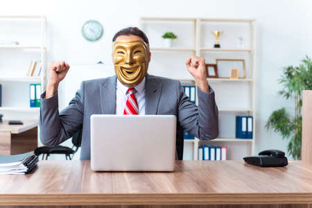 Businessman wearing mask in hypocrisy conceptの写真素材