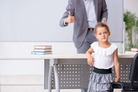 Teacher with young girl in the classroomの写真素材