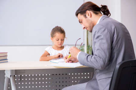 Teacher with young girl in the classroomの写真素材