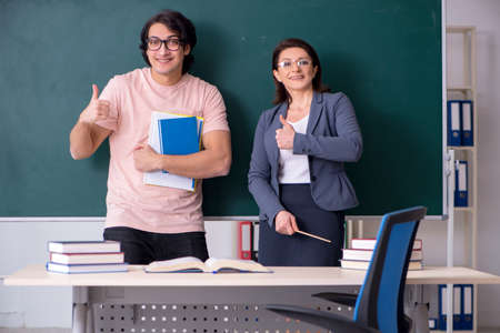 Old female teacher and male student in the classroomの写真素材