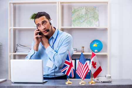 Young male travel agent working in the officeの写真素材