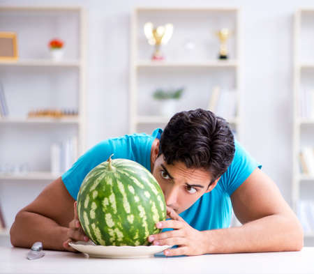 Man eating watermelon at homeの写真素材