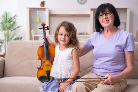 Old lady teaching little girl to play violin