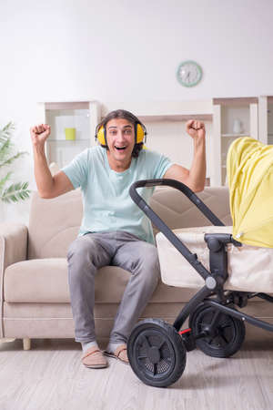 Young man looking after baby in pramの写真素材