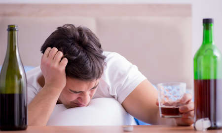 Man alcoholic drinking in bed going through break up depression