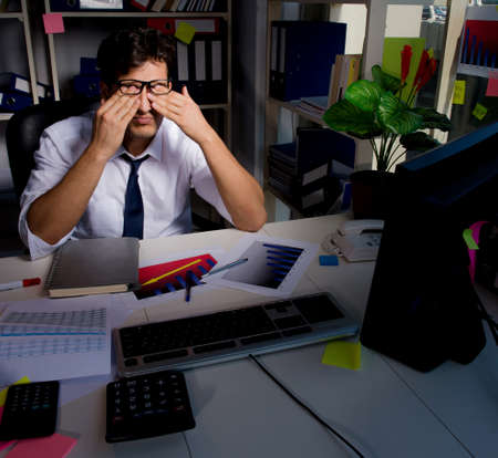 Man businessman working late hours in the officeの写真素材
