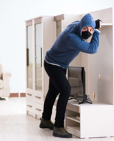 Man burglar stealing tv set from houseの写真素材