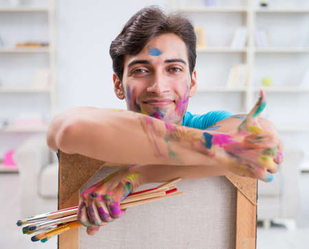 Young funny artist working on new painting in his studioの写真素材