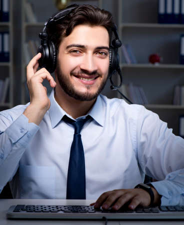 Young man in call center concept working late overtime in office