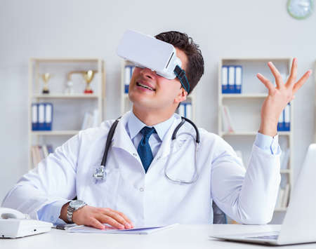 Young doctor with vr virtual reality headset working in the offiの写真素材