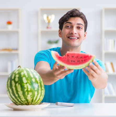 Man eating watermelon at homeの写真素材