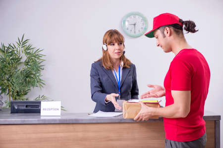 Young male courier delivering box to hotels reception