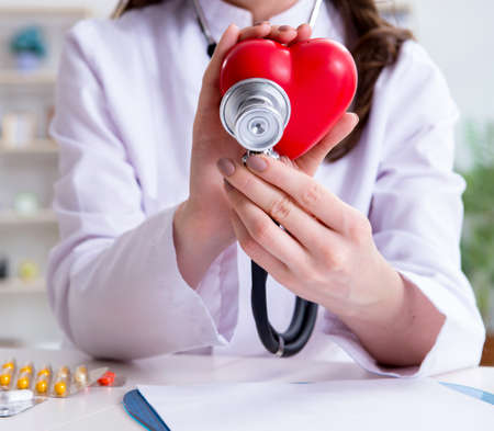 Doctor cardiologist with red heart in the hospitalの写真素材