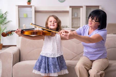 Old lady teaching little girl to play violinの写真素材