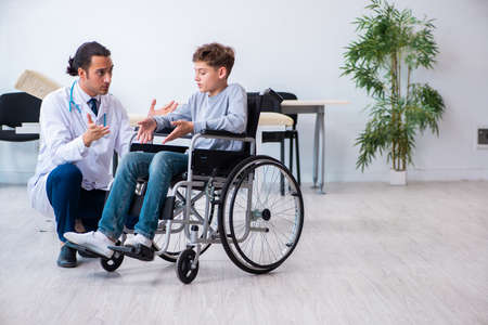 Young male doctor pediatrist and boy in wheel-chair