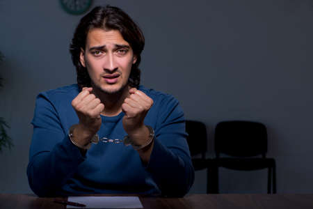 Young convict man sitting in dark room