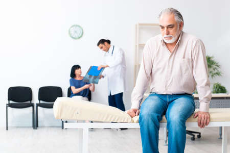 Old couple visiting young male doctorの写真素材