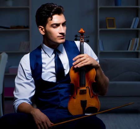 Young musician man practicing playing violin at homeの写真素材
