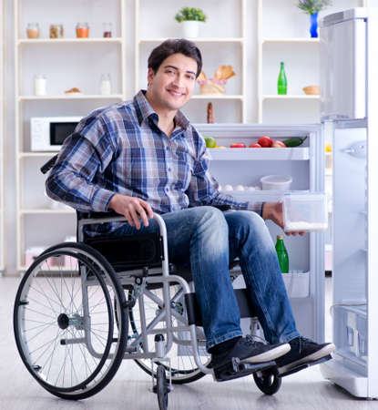 Young disabled injured man opening the fridge door