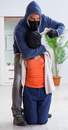 Armed man assaulting young woman at homeの写真素材