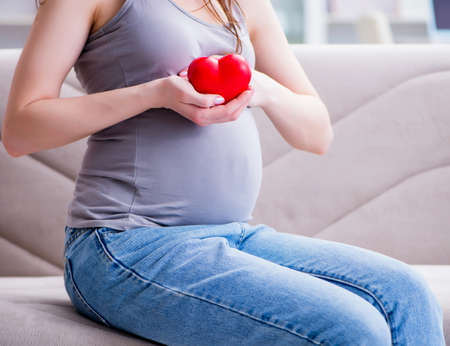 Pregnant woman with a belly tummy sitting on a sofa at home