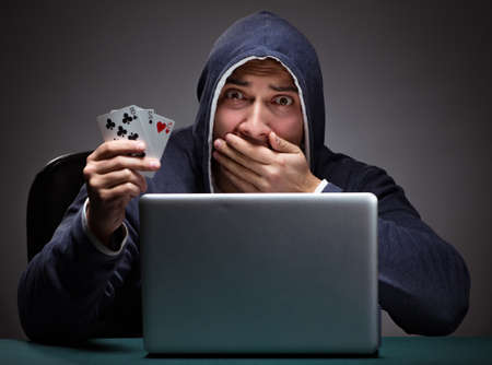Young man wearing a hoodie sitting in front of a laptop computerの写真素材