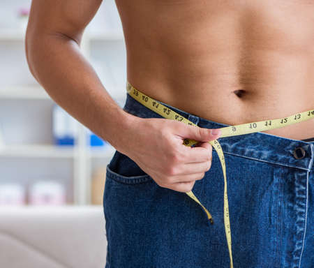 Man in oversized pants in weight loss conceptの写真素材
