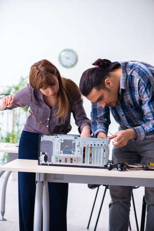 Two repairmen repairing desktop computerの写真素材