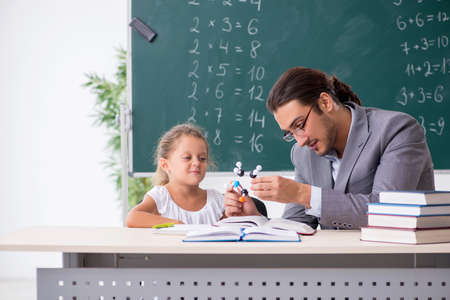 Teacher with young girl in the classroomの写真素材