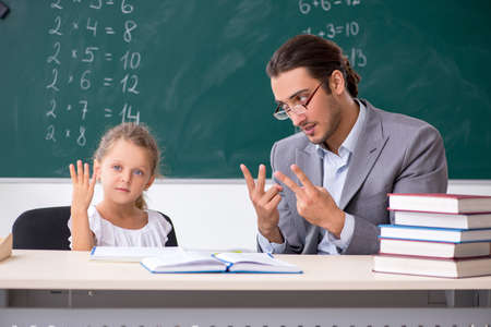 Teacher with young girl in the classroomの写真素材