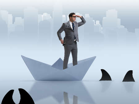 Businessman looking into future with binoculars in paper ship boの写真素材