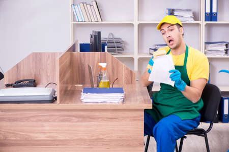 Young male contractor cleaning the officeの写真素材