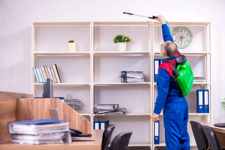 The old professional contractor doing pest control in the officeの写真素材