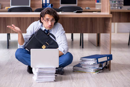 Young male employee and too many work in the officeの写真素材