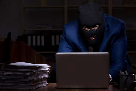 The male employee stealing information in the office night timeの写真素材