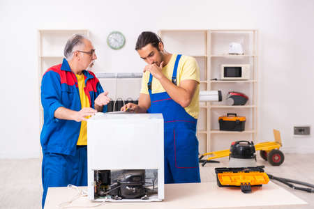 Two contractors repairing fridge at workshopの写真素材