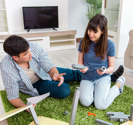 Young family assembling furniture at new houseの写真素材