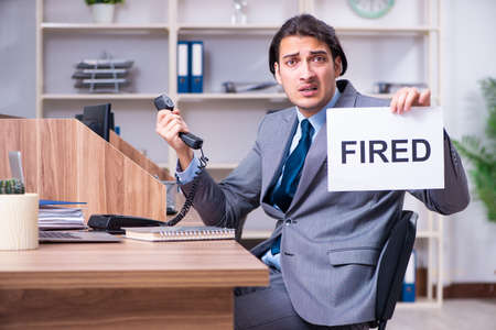Young male employee being fired from his workの写真素材
