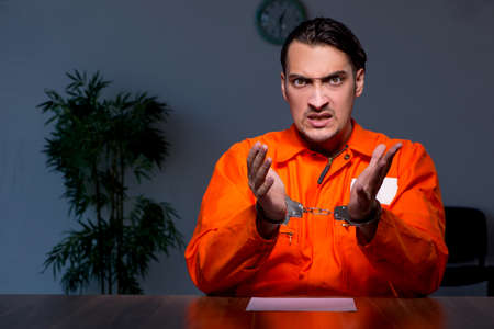 Young convict man sitting in dark roomの写真素材