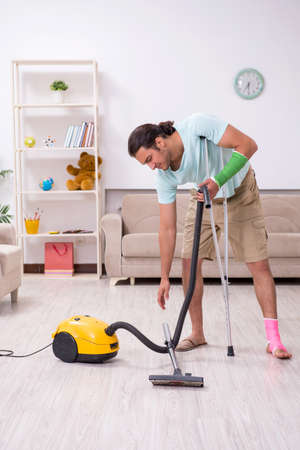 Young injured man cleaning the houseの写真素材