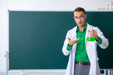 Young male chemist teacher in front of blackboardの写真素材