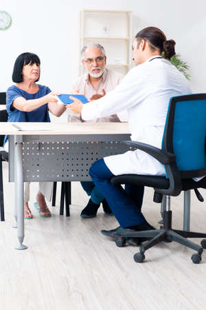 Old couple visiting young male doctorの写真素材