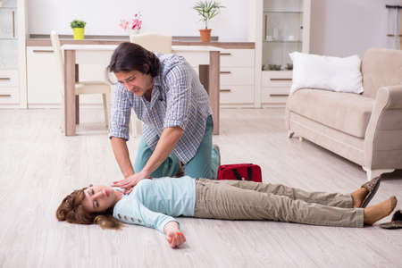 Young couple in first aid concept at homeの写真素材