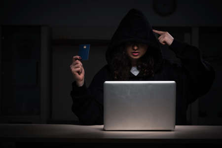 Female hacker hacking security firewall late in officeの写真素材