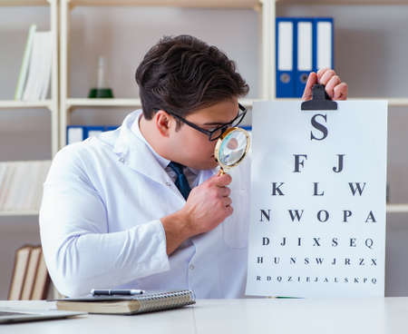 The doctor optician with letter chart conducting an eye test checkの写真素材