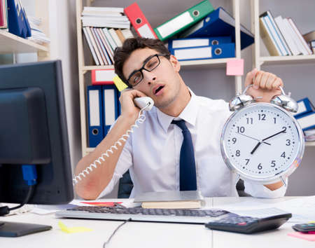 Businessman working in the office with piles of books and papersの写真素材