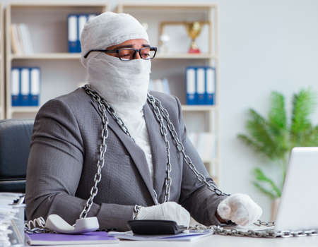 Bandaged businessman worker working in the office doing paperworkの写真素材