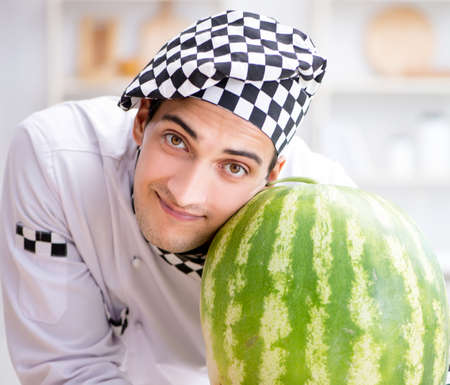 Male cook with watermelon in kitchenの写真素材