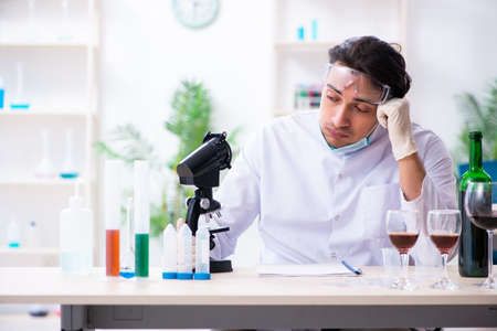 Male chemist examining wine samples at labの写真素材
