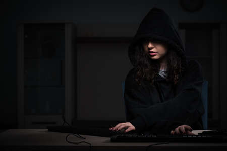 Female hacker hacking security firewall late in officeの写真素材